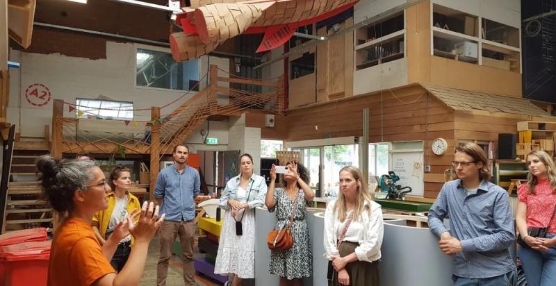 Kennissessie bij Buurman Rotterdam, een vrouw geeft een praatje aan de groep mensen die wordt rondgeleid in de werkplaats