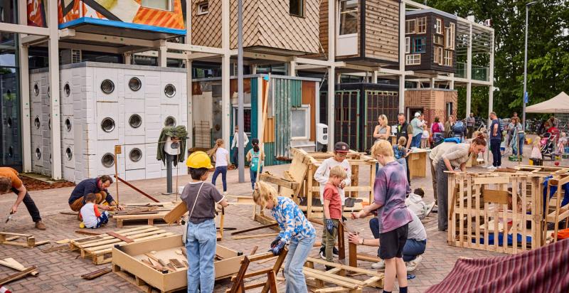 Groep kinderen is op het parkeerterrein van circulair centrum De HER aan het timmeren.