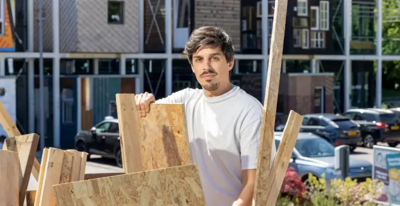 Ondernemer Kristiyan Dyankov bij de houtcontainer met op de achtergrond circulair centrum De HER.