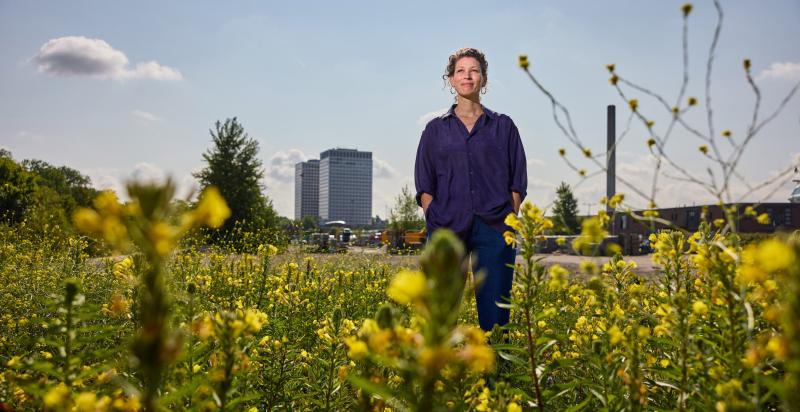 Sophie Duran in een veld vol gele bloemen met op de achtergrond de Marconi torens