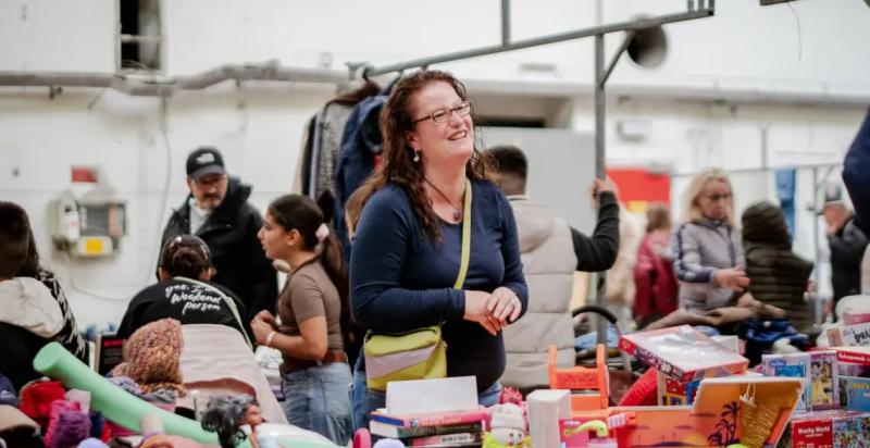 Vrouw glimlacht vanachter haar kraam op een markt