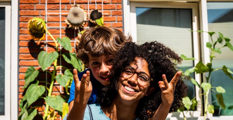 Twee kinderen poseren lachend voor zonnebloemen