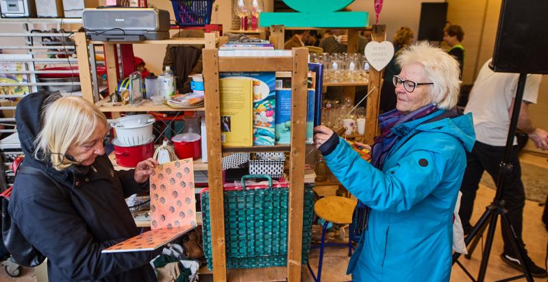 Twee oudere dames bekijken spullen in een weggeefwinkel.