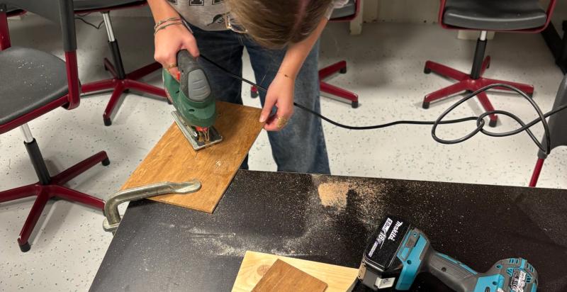 Jonge vrouw zaagt stuk hout.