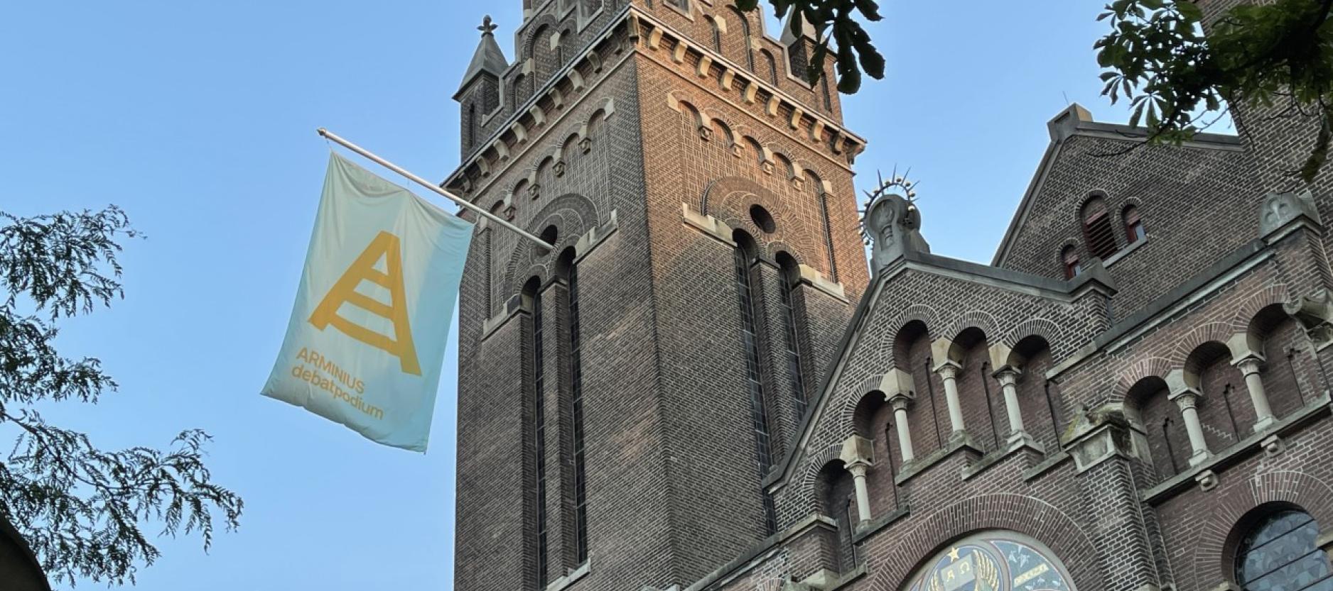 Arminiuskerk in Rotterdam met een vlag aan de gevel van Arminius debat