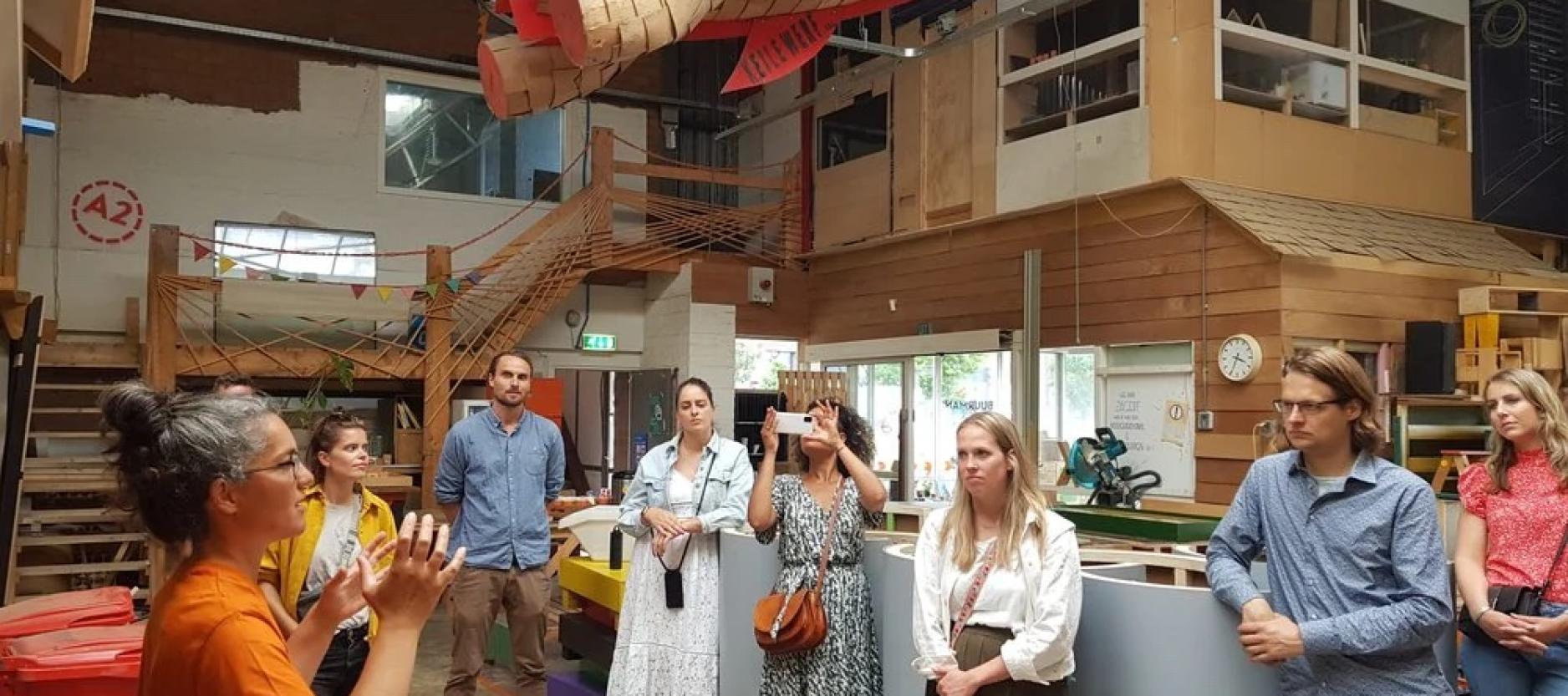 Kennissessie bij Buurman Rotterdam, een vrouw geeft een praatje aan de groep mensen die wordt rondgeleid in de werkplaats