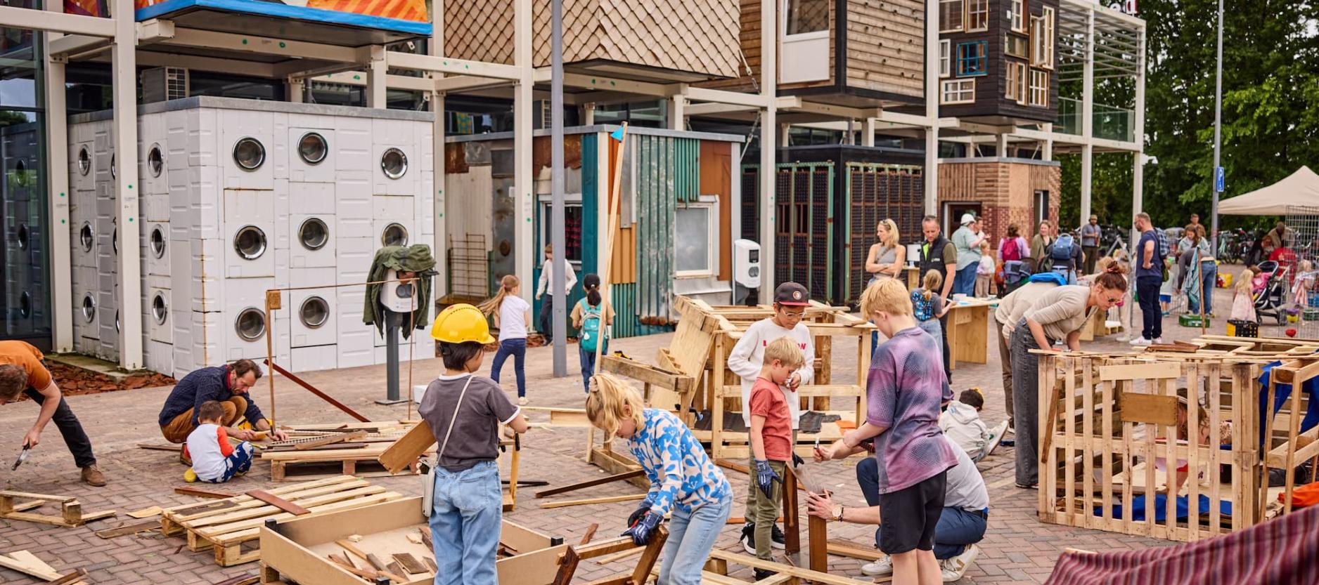 Groep kinderen is op het parkeerterrein van circulair centrum De HER aan het timmeren.