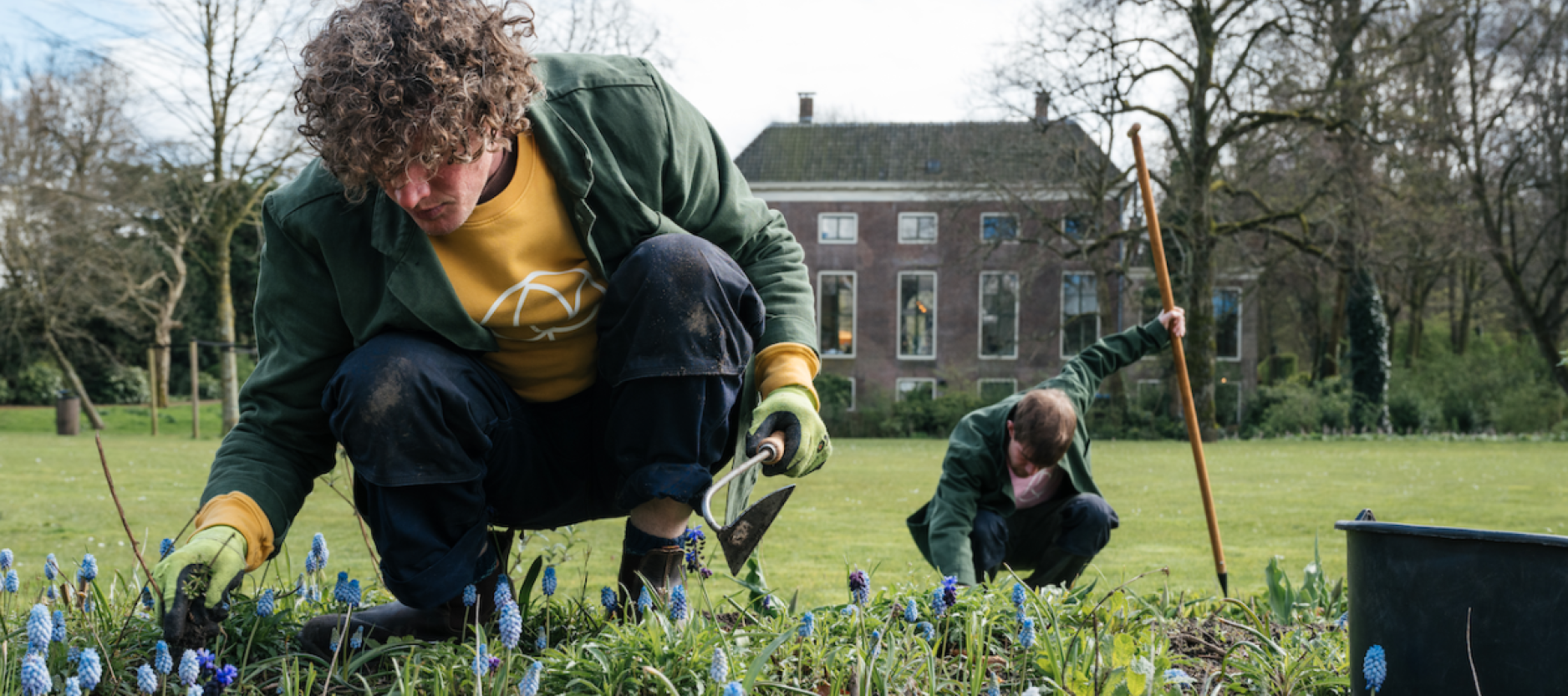 Twee mensen werken in de tuin voor een mooi monumentaal pand