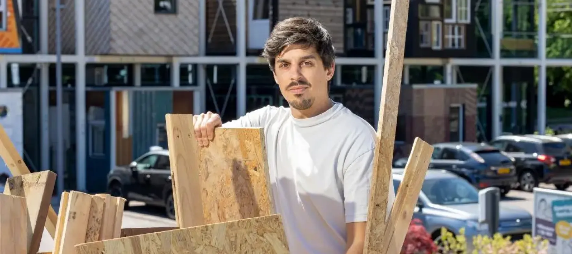 Ondernemer Kristiyan Dyankov bij de houtcontainer met op de achtergrond circulair centrum De HER.