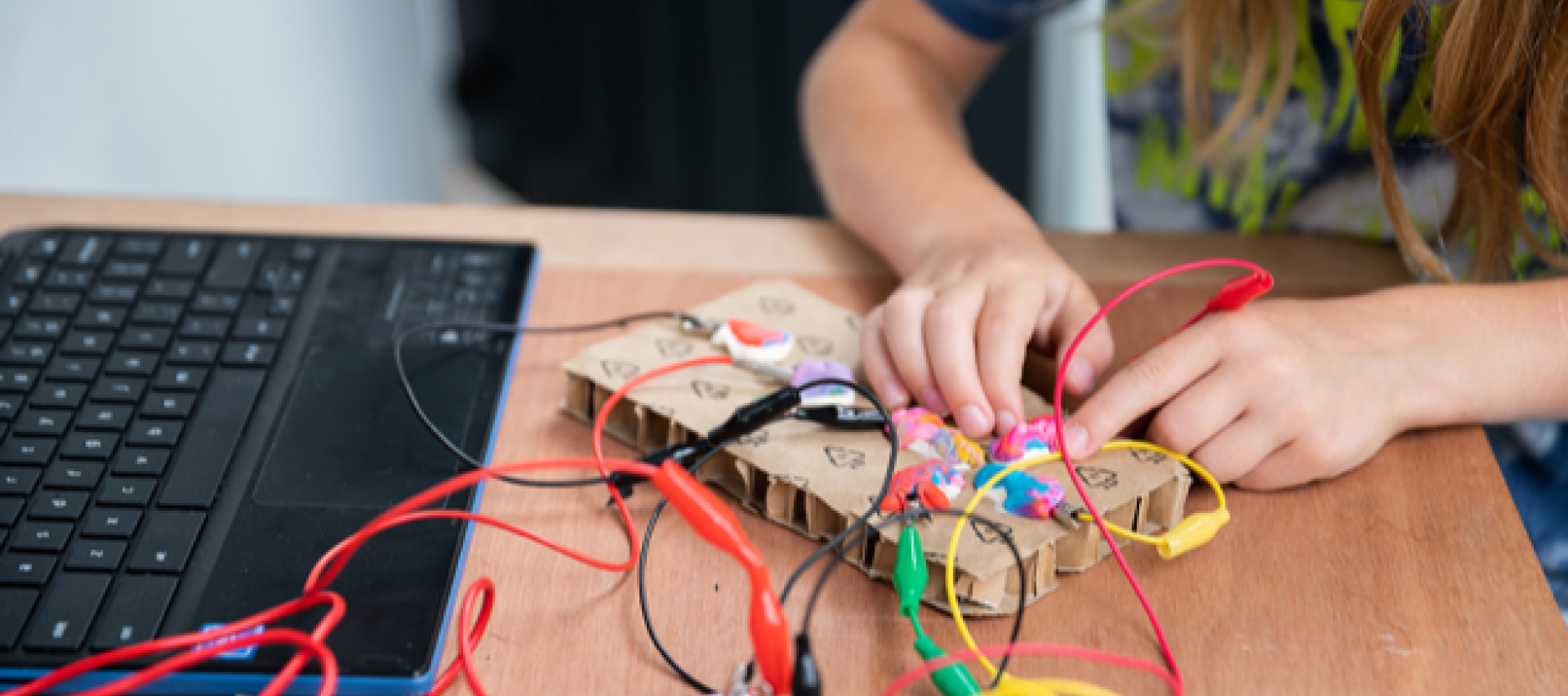 Een kind zit aan tafel en knutselt met allerlei materialen.