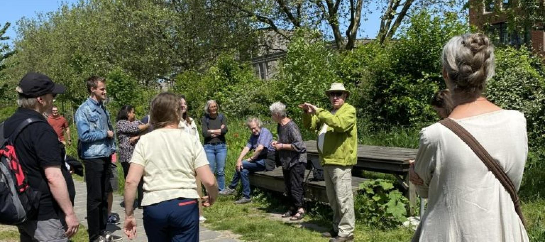 mensen krijgen een rondleiding in een park, een meneer geeft uitleg