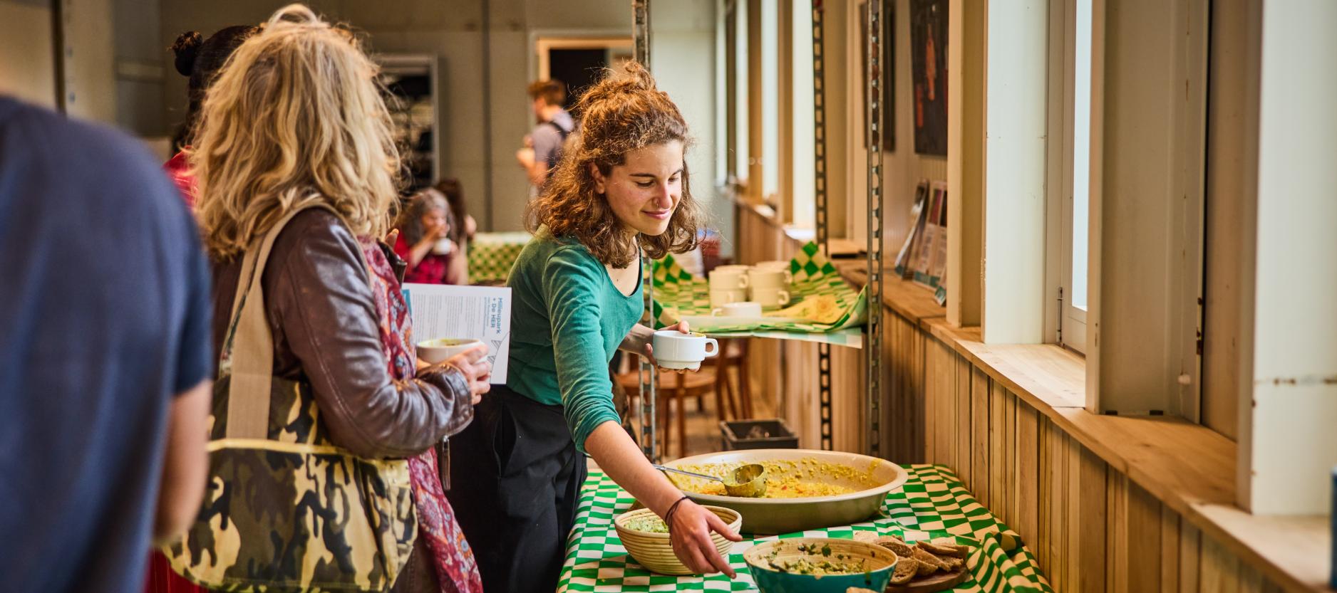 Vrouw schept eten op bij een buffet in De HER.