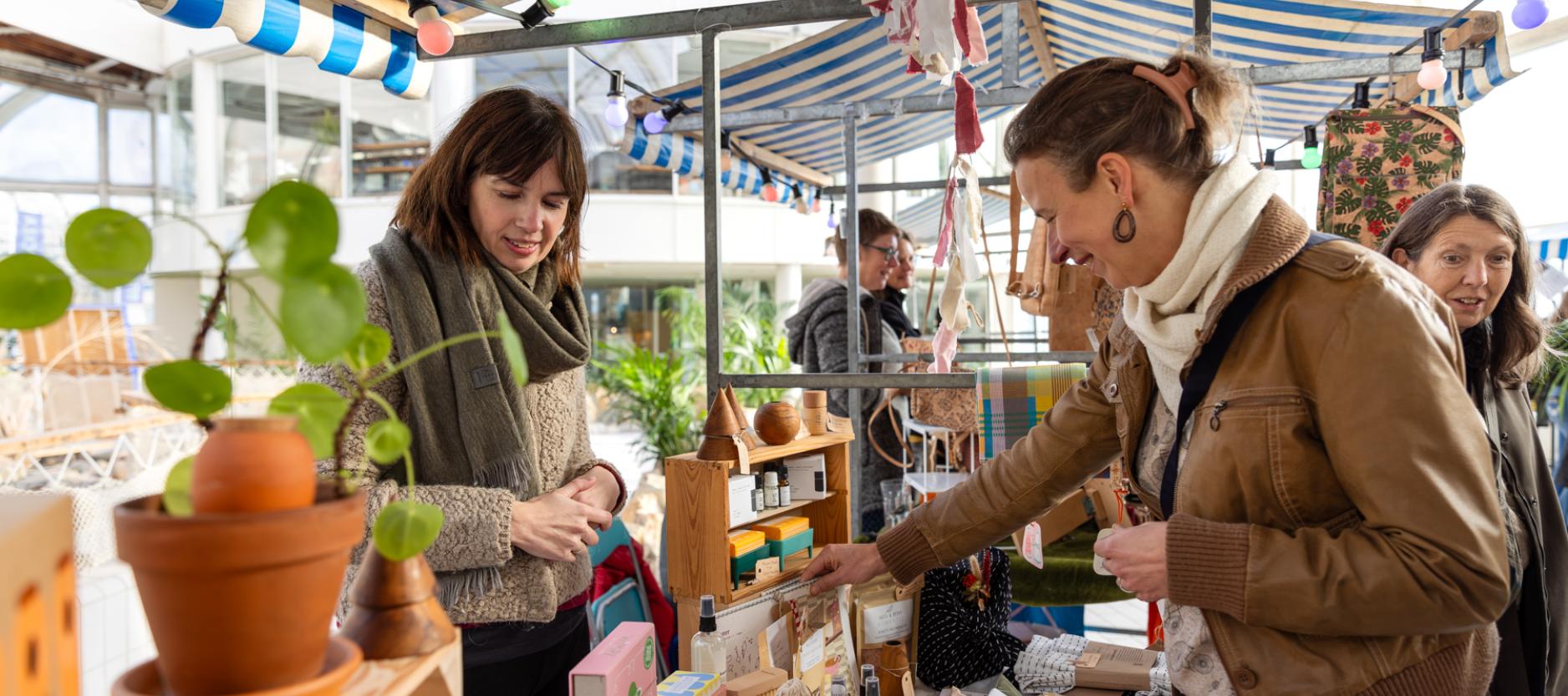 Vrouw kijkt naar producten bij een marktkraam in BlueCity tijdens het evenement Changez.