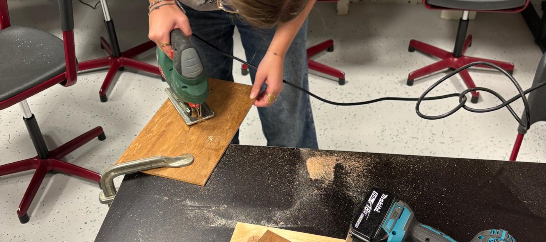 Jonge vrouw zaagt stuk hout.