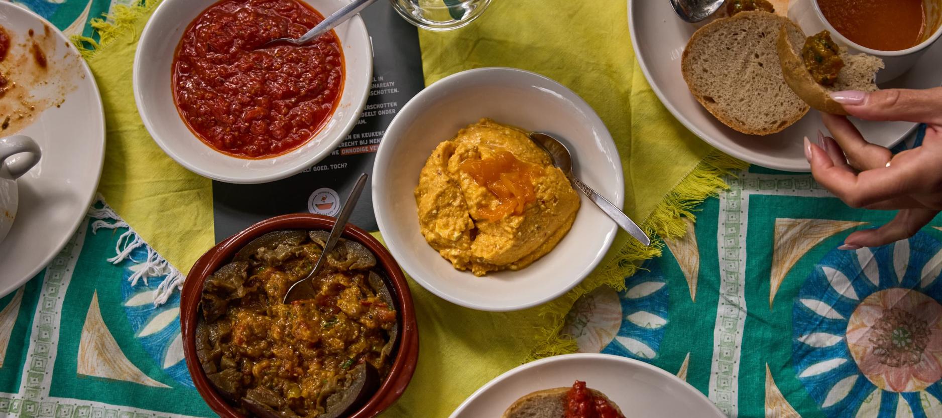 Op een tafel staan een aantal bakjes met dips van bijvoorbeeld olijven.