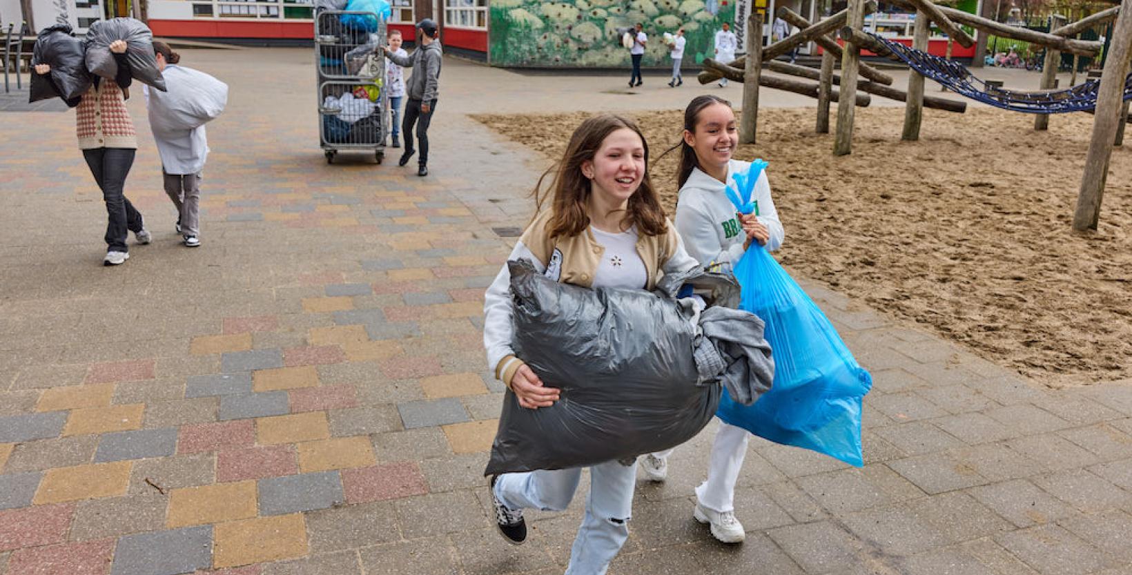 Leerlingen op het schoolplein met zakken vol textiel