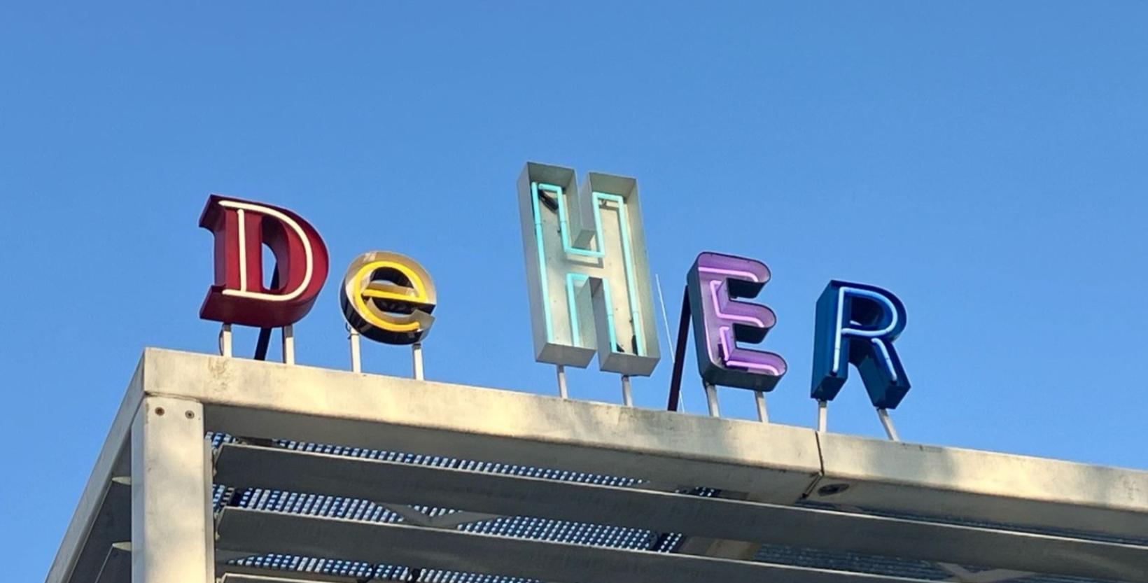 Neonletters De HER op het dak van het pand.