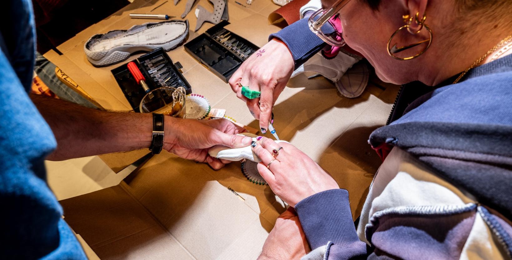 Vrouw is aan een een tafel bezig om een oude sneaker uit elkaar te halen.