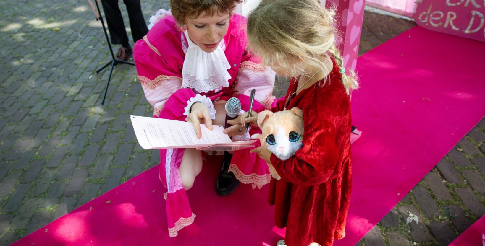 Vrouw hurkt bij een klein meisje met een knuffel in haar hand.