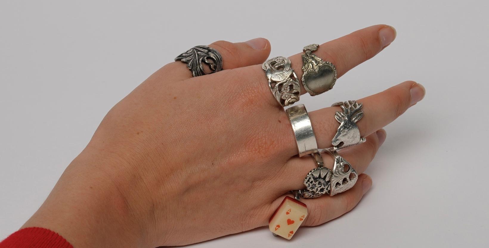 Een vrouwenhand met aan de vingers een heleboel ringen gemaakt van theelepels.