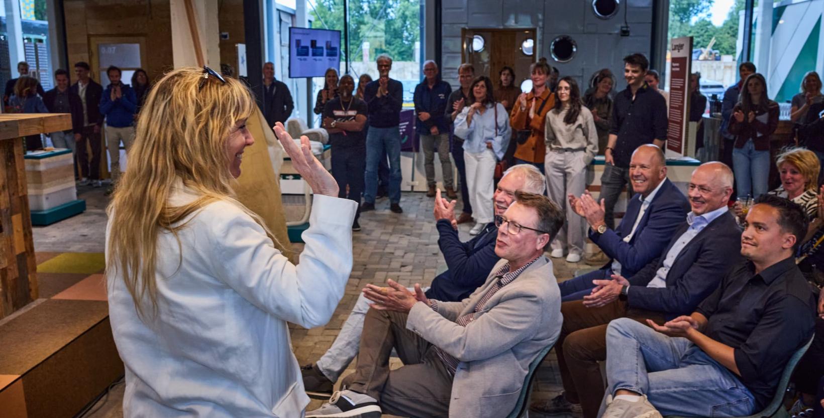 Een groep mensen klapt voor de projectmanager van circulair centrum De HER.