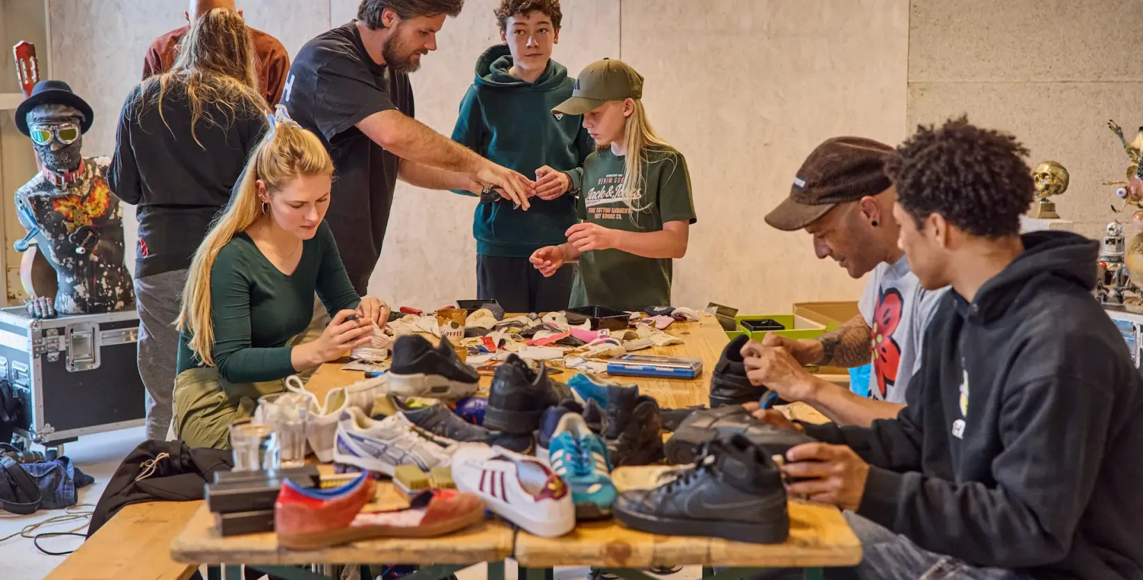 Groep mensen zit rond een tafel sneakers uit elkaar te halen.
