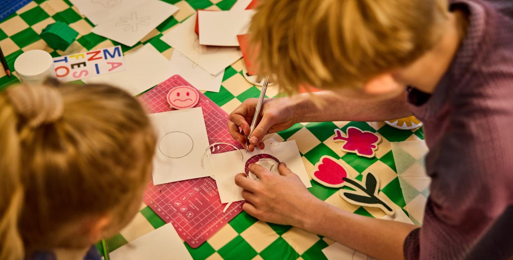 Twee meisjes zijn samen een ontwerpje aan het maken voor een zeefdruk.