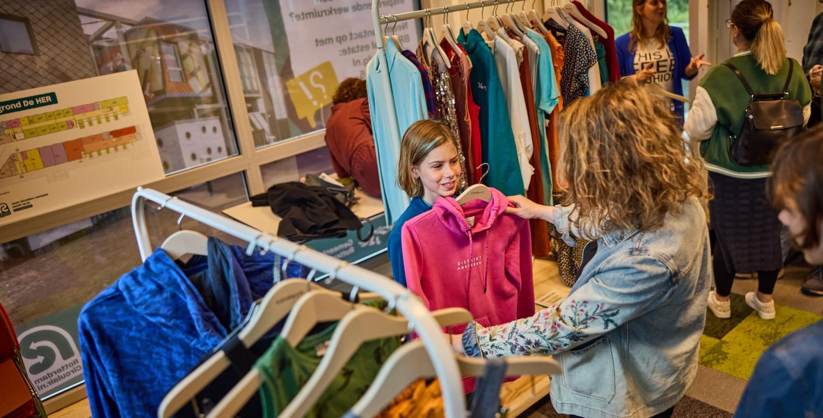 Een moeder en dochter neuzen in de rekken gratis kleding.
