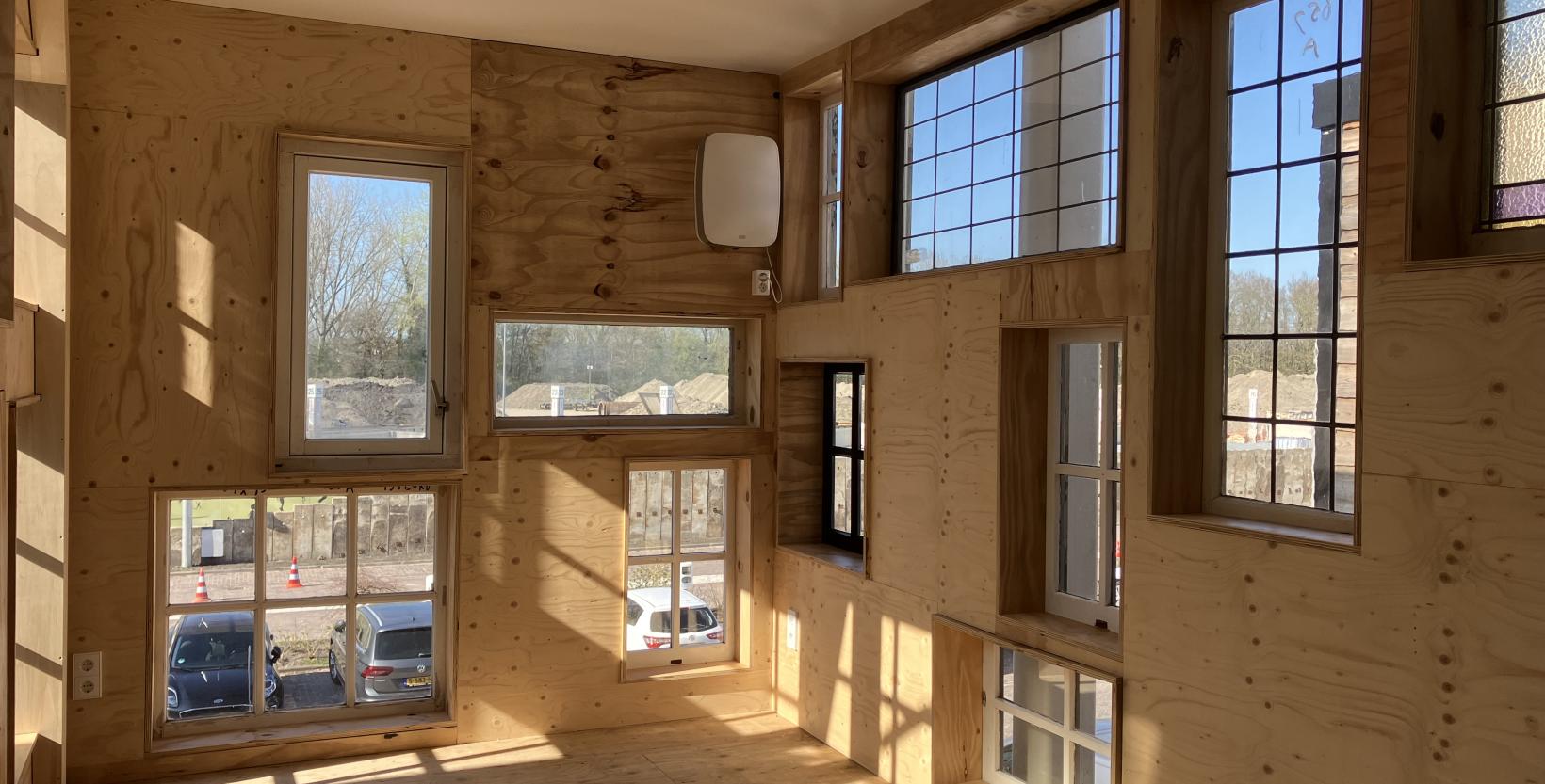 Een van de werkruimtes van circulair centrum De HER. Deze is gemaakt met allerlei oude raamkozijnen erin.