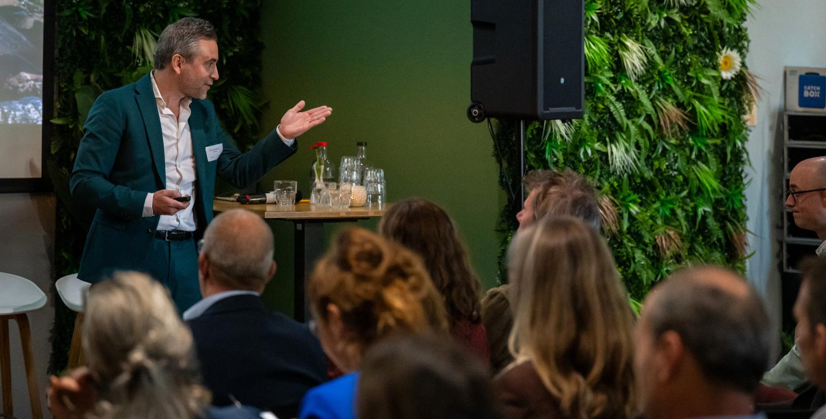 Evert-Jan de Kort spreekt een zaal met mensen toe.